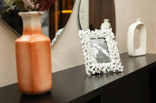 Decorative orange vase, white photo frame, and modern ceramic vase